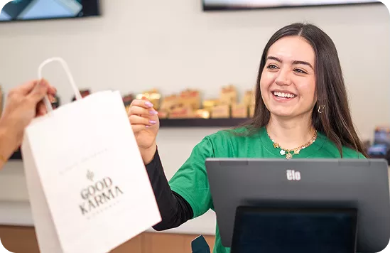 Woman in green shirt holding white shopping bag with Good Karma logo