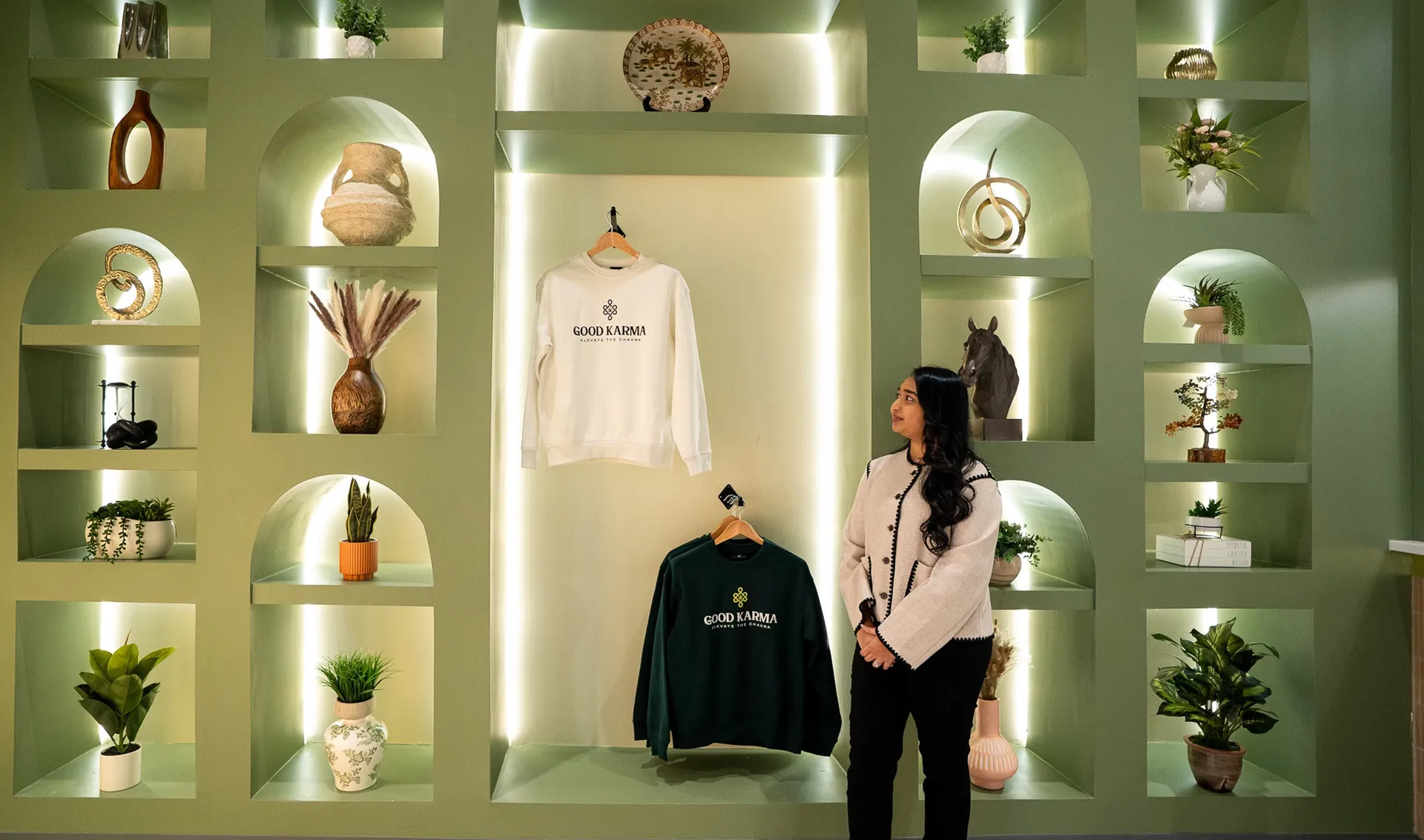 Woman standing beside clothing and decorative items on shelves in a store