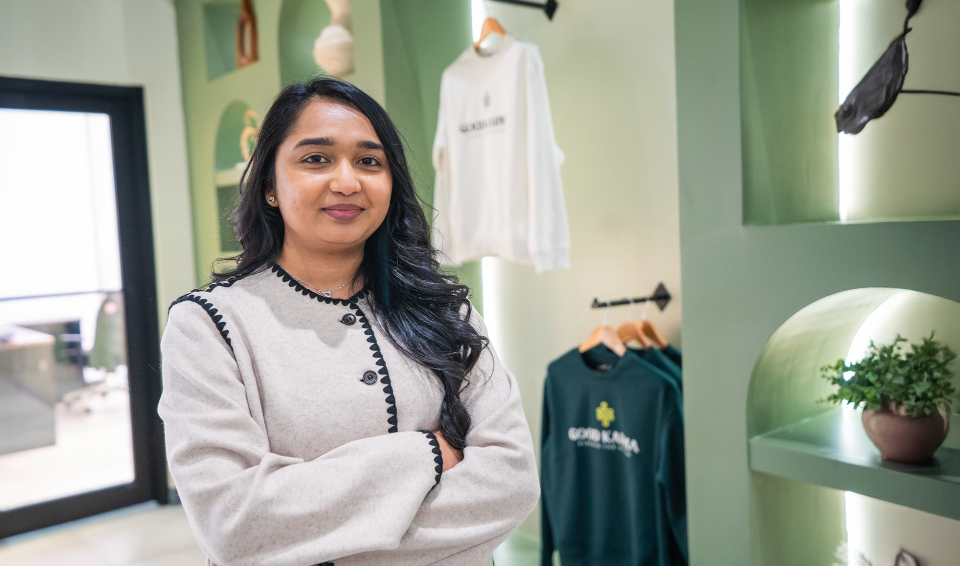 Woman standing in cannabis dispensary with her arms crossed, smiling